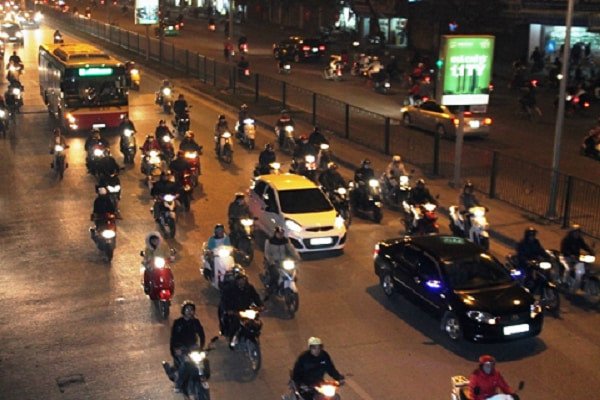 Hình ảnh xe ô tô bật đèn chiếu sáng khi lái xe vào ban đêm trong khu vực đô thị đông dân cư