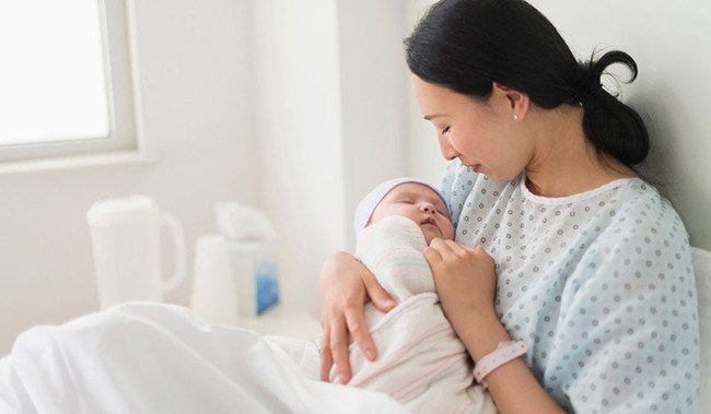 Hình ảnh minh họa người mẹ chăm sóc em bé sau sinh, liên quan chế độ phục hồi sức khỏe