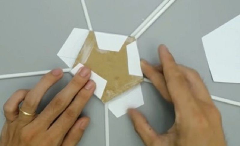 Gấp và dán mép giấy thừa ra phía sau để hoàn thiện mặt đáy cho ống đựng bút từ ống hút tái chế.