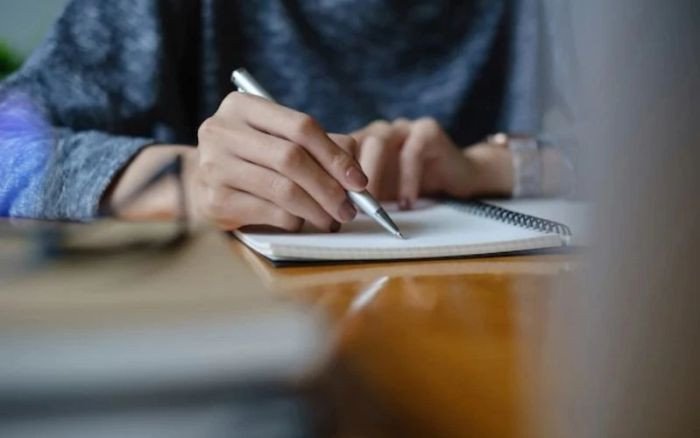 Học sinh nữ đang chăm chú học tiếng Anh với máy tính bảng và sổ ghi chép, thể hiện sự tập trung vào kế hoạch học tập hiệu quả.