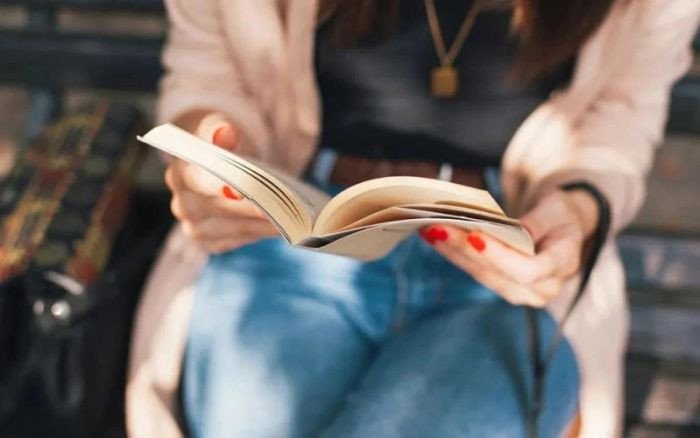 Một nhóm người đang ngồi xung quanh bàn với nhiều sách và máy tính, thể hiện việc học tập và chia sẻ kiến thức.