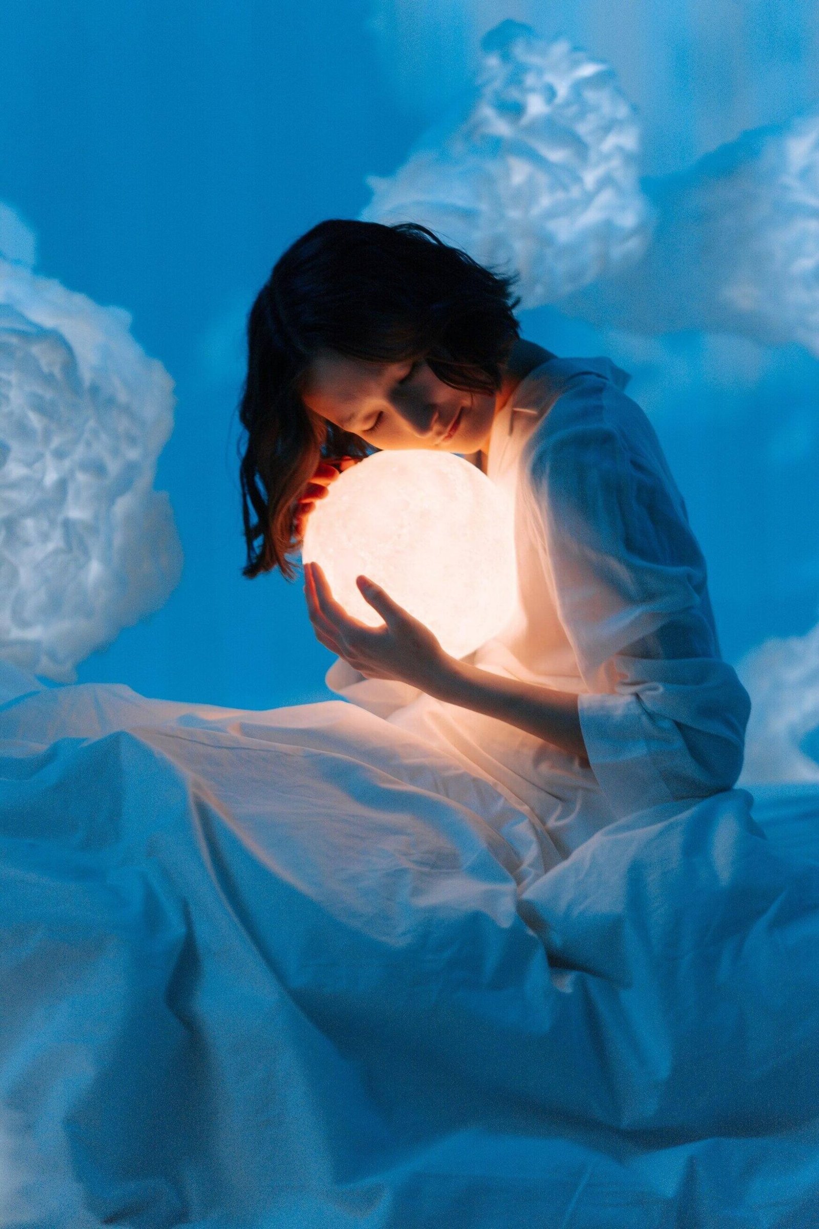 Cô gái ôm đèn ngủ, biểu hiện sự tò mò về ý nghĩa giấc mơ thấy người lạ nói chuyện