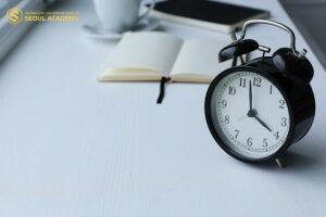 Đồng hồ báo thức và sách vở, biểu tượng cho việc quản lý thời gian hiệu quả giúp học sinh ứng phó với áp lực học tập.