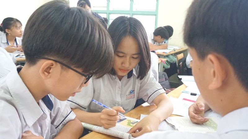 Hình ảnh một bạn học sinh đang chăm chỉ viết bài trong vở, bàn học gọn gàng với sách và dụng cụ, tượng trưng cho sự nỗ lực cá nhân