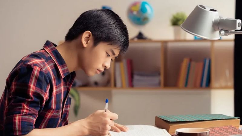 Học sinh nam nhìn ra cửa sổ trong giờ học, thể hiện sự xao nhãng và mất tập trung