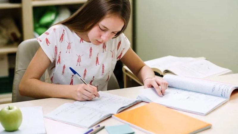 Học sinh nữ ngồi trước màn hình máy tính với vẻ mặt mệt mỏi và chán nản, thiếu động lực học tập