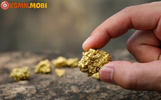 Mơ thấy lượm vàng là điềm gì: Hình ảnh người phụ nữ đang ngắm nhìn thỏi vàng lấp lánh, tượng trưng cho những điềm báo tài lộc và may mắn trong cuộc sống.