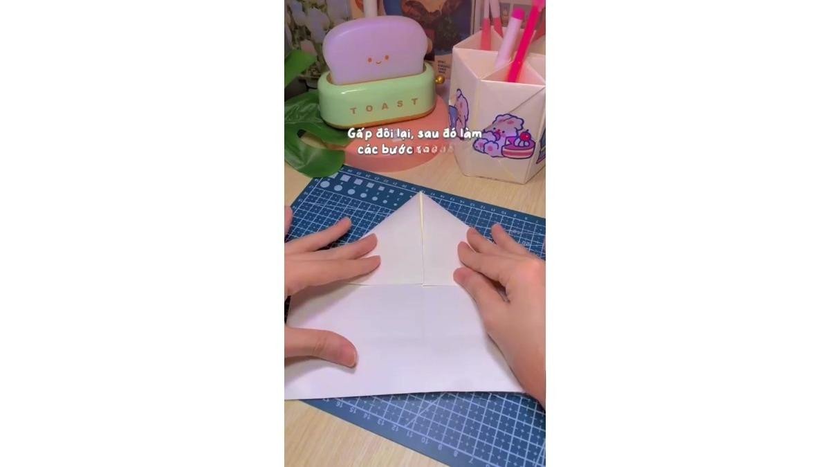 Mở tờ giấy A4 ra và gấp 2 cạnh nửa trên sao cho chạm mép với nếp ở bước đầu