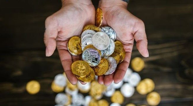 Một bàn tay đang nhận những thỏi vàng lấp lánh từ một bàn tay khác