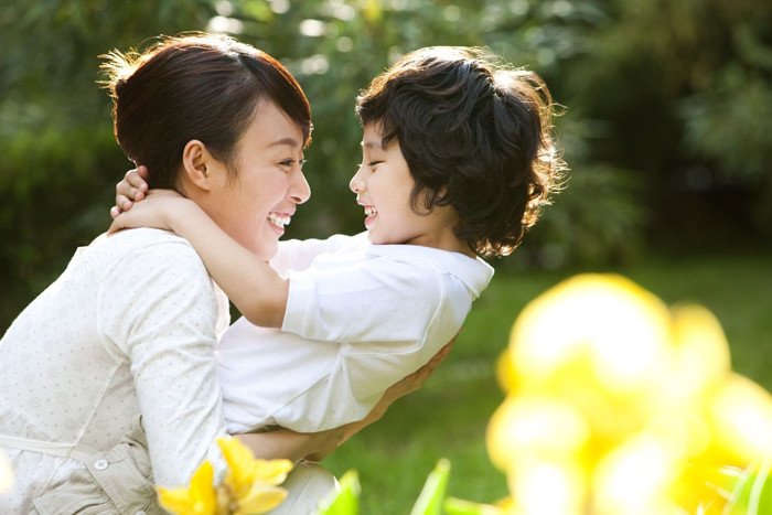 Một người phụ nữ lớn tuổi đang bế một em bé cười tươi