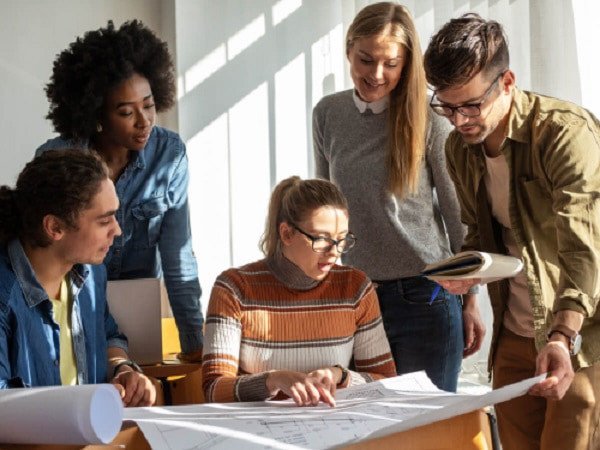 Một nhóm sinh viên đang làm việc cùng nhau trên laptop, thảo luận và hỗ trợ lẫn nhau trong học tập