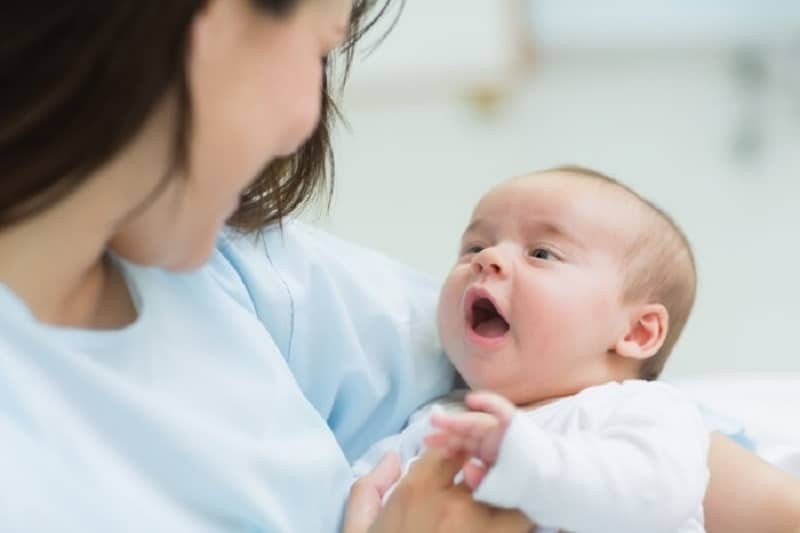Người mẹ ôm ấp em bé trai đang khóc, thể hiện sự quan tâm và lo lắng