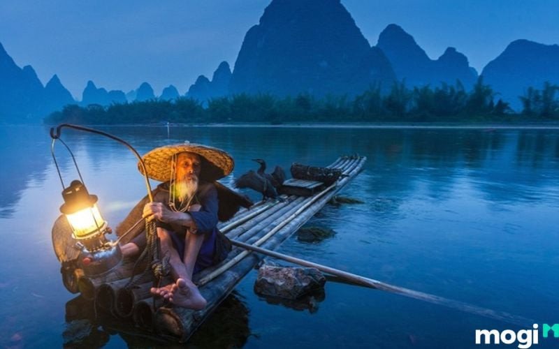 Người phụ nữ đang dùng tay không bắt cá dưới ao bùn, thể hiện giấc mơ bắt cá ở sông, hồ
