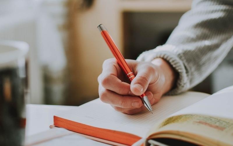 Bàn tay viết bài trong đêm, nhấn mạnh tầm quan trọng của sự kiên trì và những câu nói truyền cảm hứng học tập hiệu quả.