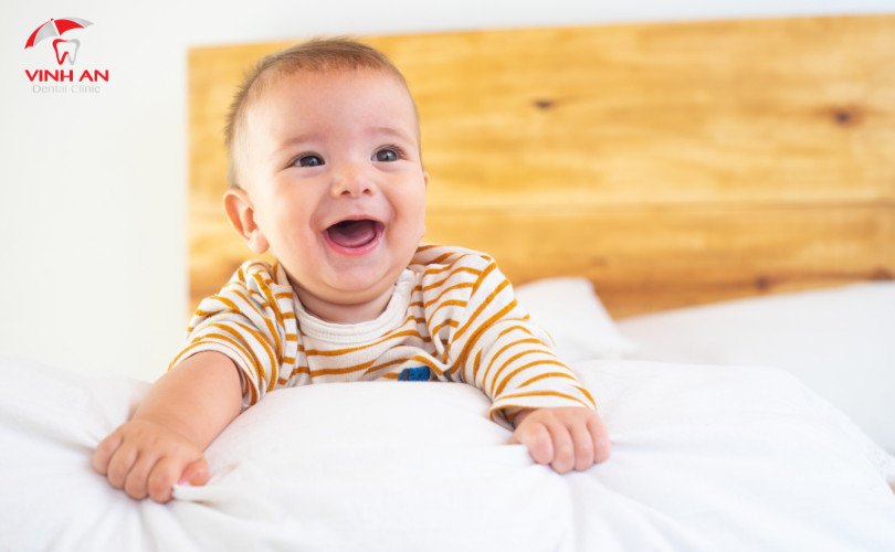 Em bé dễ thương đang cười, thể hiện những chiếc răng đầu tiên mọc lên trong giấc mơ